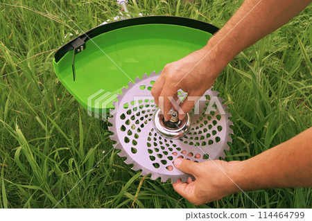 Installing a saw blade on a new green brush cutter. Installing a saw blade on a new green brush cutter. 114464799
