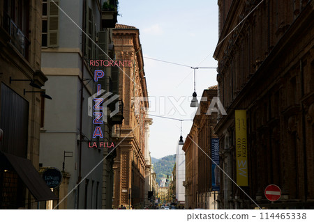 TURIN, ITALY - SEP 14, 2019: Walking in the streets of the old town of Turin. Houses with neon pizza signs 114465338