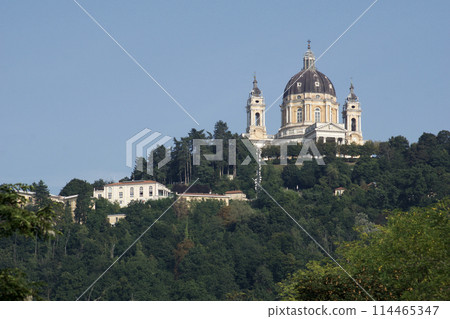 TURIN, ITALY - SEP 14, 2019: Superga, actually Basilica della Nativita di Maria Vergine, an important pilgrimage church near Turin in Italy, photographed from a distance with trees 114465347