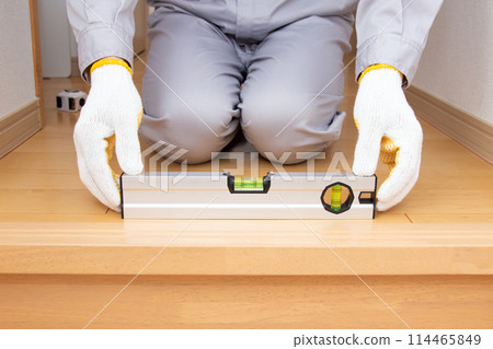 A contractor who checks floor level using a level gauge 114465849