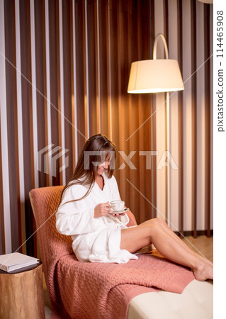 happy young oman in bathrobe sitting and holding a coffee cup. 114465908