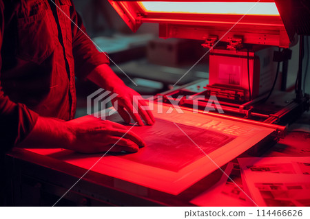 A man is working on a piece of paper with a red background 114466626