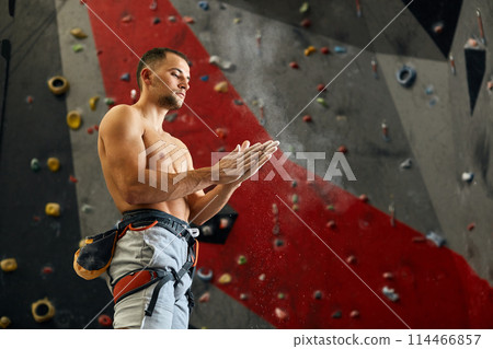 Climber coating his hands in powder chalk magnesium to climb indoor, close-up Climber coating his hands in powder chalk magnesium to climb indoor, close-up 114466857