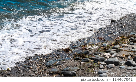 The ocean waves are crashing against the rocks, creating a beautiful and serene scene. The water is a deep blue color, and the rocks are scattered throughout the beach. Scene is peaceful and calming. The ocean waves are crashing against the rocks, creating a beautiful and serene scene. The water is a deep blue color, and the rocks are scattered throughout the beach. Scene is peaceful and calming. 114467041
