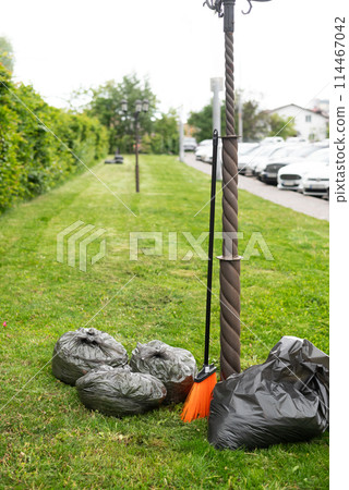 Mowing the grass. Work on the territory, spring cleaning. Garden and lawn care. Cleaning mowed grass into black plastic bags. 114467042