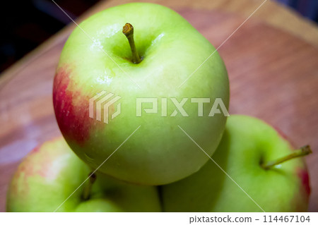 Organic Apple Display. Green apples, one in focus, on a rustic wood backdrop. Organic Apple Display. Green apples, one in focus, on a rustic wood backdrop. 114467104