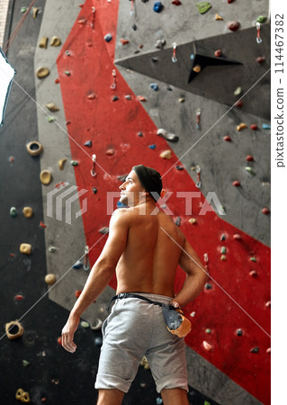 Back side of athlete man standing next to wall, ready for rock climbing. Back side of athlete man standing next to wall, ready for rock climbing. 114467382