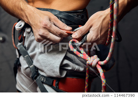 Climber s male hands with equipment during preparation for climb, close-up. 114467390