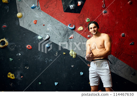 Portrait of cheerful rock climber in indoor climbing gym Portrait of cheerful rock climber in indoor climbing gym 114467630