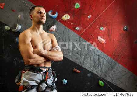 Portrait of cheerful rock climber in indoor climbing gym Portrait of cheerful rock climber in indoor climbing gym 114467635
