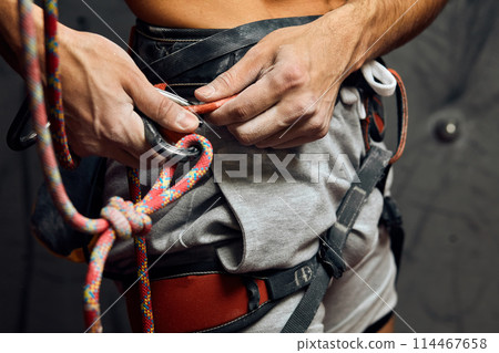 Climber s male hands with equipment during preparation for climb, close-up. 114467658