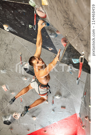 Male professional climber at indoor workout at bouldering centre. 114468459