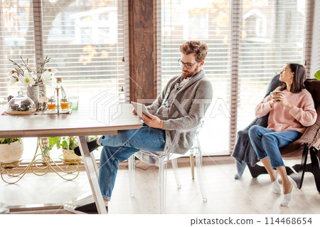 Couple in kitchen spending time together with cup of coffee and smartphone 114468654