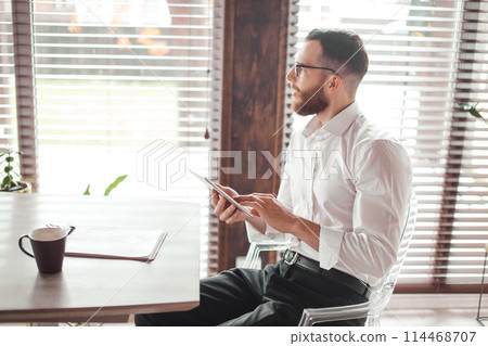 Serious applicant sitting in boardroom, preparing for interview with employer. Serious applicant sitting in boardroom, preparing for interview with employer. 114468707
