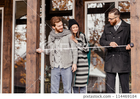 Real estate broker and clients standing next to new house Real estate broker and clients standing next to new house 114469184