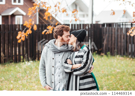 Happy young couple sitting outdoor, in front of their new home in autumn day 114469314