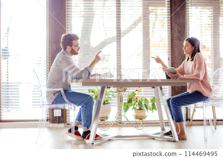 Couple sharing ideas, sitting opposite near big window. 114469495