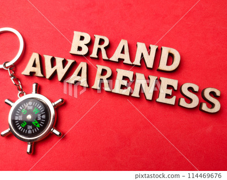 Top view compass and wooden word with text BRAND AWARENESS on red background. 114469676