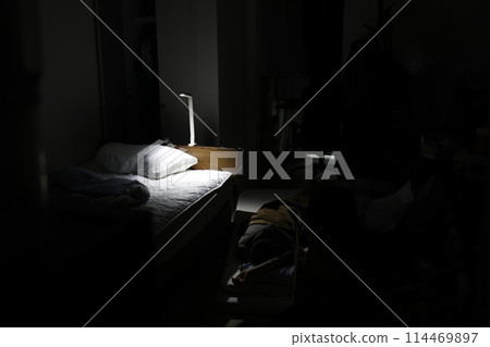 In a room with only the bed light on 114469897