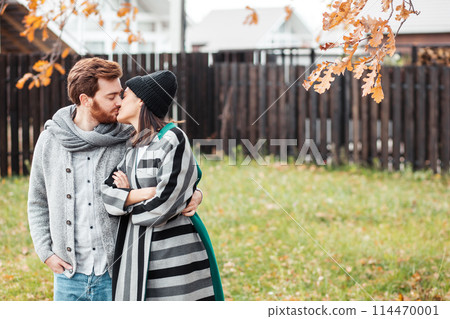 Happy young couple sitting outdoor, in front of their new home in autumn day Happy young couple sitting outdoor, in front of their new home in autumn day 114470001