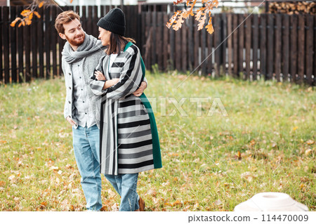 Happy young couple sitting outdoor, in front of their new home in autumn day Happy young couple sitting outdoor, in front of their new home in autumn day 114470009