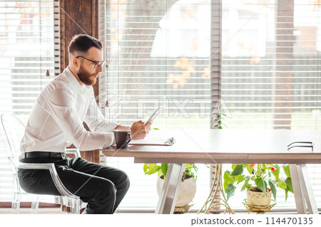 Serious applicant sitting in boardroom, preparing for interview with employer. Serious applicant sitting in boardroom, preparing for interview with employer. 114470135