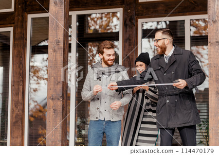 Real estate broker and clients standing next to house Real estate broker and clients standing next to house 114470179