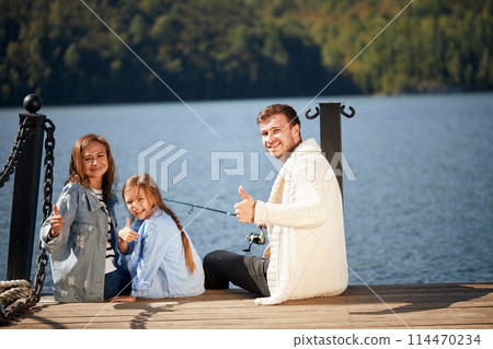 happy family with daughter fishing in pond in fall happy family with daughter fishing in pond in fall 114470234