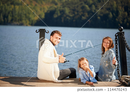 happy family with daughter fishing in pond in fall 114470243