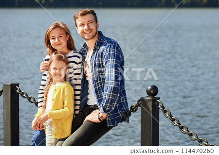Happy Family looking at camera while posing on pier at quiet lake 114470260