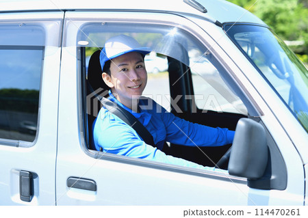 A male delivery driver carrying luggage outdoors 114470261