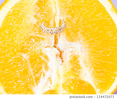 Intimate piercing. Minimal piercing concept. Orange with piercing close-up Intimate piercing. Minimal piercing concept. Orange with piercing close-up 114472071