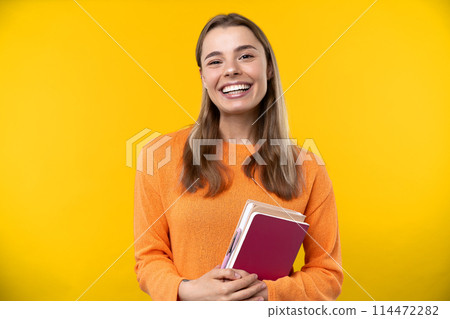 Happy emotions concept. Positive and beautiful young woman laughs poisitively looks aside with carefree face expression wears casual orange sweater isolated over yellow studio background. Happy emotions concept. Positive and beautiful young woman laughs poisitively looks aside with carefree face expression wears casual orange sweater isolated over yellow studio background. 114472282