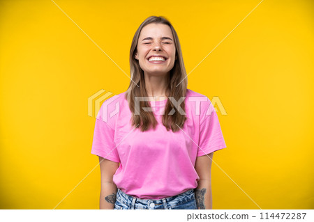 Happy emotions concept. Positive and beautiful young woman laughs poisitively looks aside with carefree face expression wears casual orange sweater isolated over yellow studio background. Happy emotions concept. Positive and beautiful young woman laughs poisitively looks aside with carefree face expression wears casual orange sweater isolated over yellow studio background. 114472287