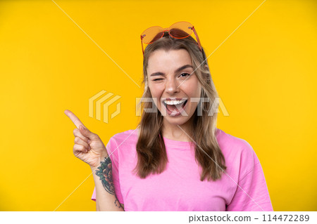 Happy emotions concept. Positive and beautiful young woman laughs poisitively looks aside with carefree face expression wears casual orange sweater isolated over yellow studio background. 114472289