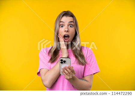 Happy emotions concept. Positive and beautiful young woman laughs poisitively looks aside with carefree face expression wears casual orange sweater isolated over yellow studio background. Happy emotions concept. Positive and beautiful young woman laughs poisitively looks aside with carefree face expression wears casual orange sweater isolated over yellow studio background. 114472290