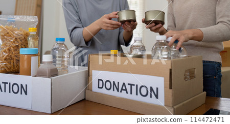 Group of volunteer woman working in home. Happy volunteer looking at food donation box separating donations stuffs 114472471