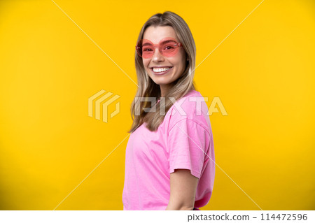 Happy emotions concept. Positive and beautiful young woman laughs poisitively looks aside with carefree face expression wears casual orange sweater isolated over yellow studio background. 114472596