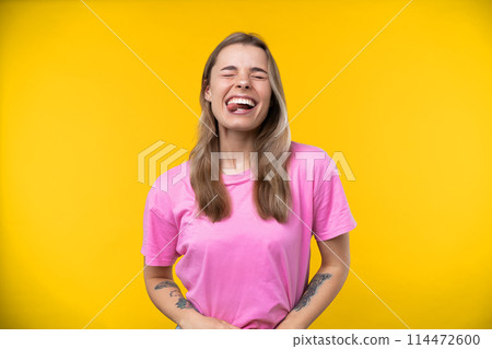 Happy emotions concept. Positive and beautiful young woman laughs poisitively looks aside with carefree face expression wears casual orange sweater isolated over yellow studio background. 114472600