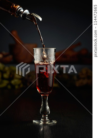 Brown herbal liquor or rum is poured from a vintage bottle. Brown herbal liquor or rum is poured from a vintage bottle. 114472665