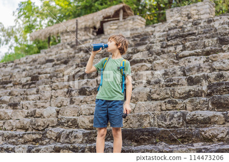 Boy tourist at Coba, Mexico. Ancient mayan city in Mexico. Coba is an archaeological area and a famous landmark of Yucatan Peninsula. Cloudy sky over a pyramid in Mexico 114473206