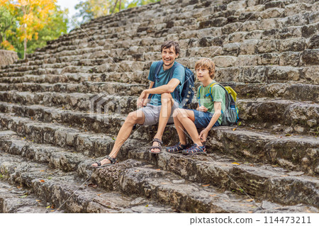Dad and son tourists at Coba, Mexico. Ancient mayan city in Mexico. Coba is an archaeological area and a famous landmark of Yucatan Peninsula. Cloudy sky over a pyramid in Mexico Dad and son tourists at Coba, Mexico. Ancient mayan city in Mexico. Coba is an archaeological area and a famous landmark of Yucatan Peninsula. Cloudy sky over a pyramid in Mexico 114473211
