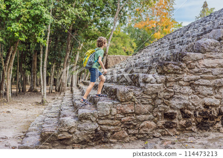Boy tourist at Coba, Mexico. Ancient mayan city in Mexico. Coba is an archaeological area and a famous landmark of Yucatan Peninsula. Cloudy sky over a pyramid in Mexico Boy tourist at Coba, Mexico. Ancient mayan city in Mexico. Coba is an archaeological area and a famous landmark of Yucatan Peninsula. Cloudy sky over a pyramid in Mexico 114473213