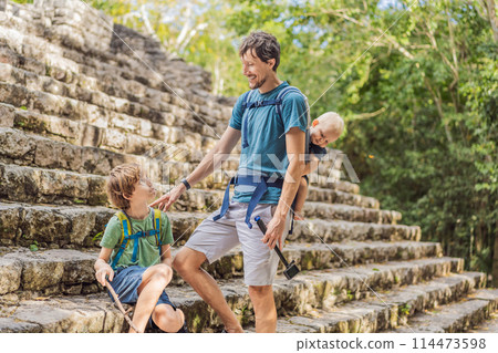 Dad with two sons tourists at Coba, Mexico. Ancient mayan city in Mexico. Coba is an archaeological area and a famous landmark of Yucatan Peninsula. Cloudy sky over a pyramid in Mexico Dad with two sons tourists at Coba, Mexico. Ancient mayan city in Mexico. Coba is an archaeological area and a famous landmark of Yucatan Peninsula. Cloudy sky over a pyramid in Mexico 114473598