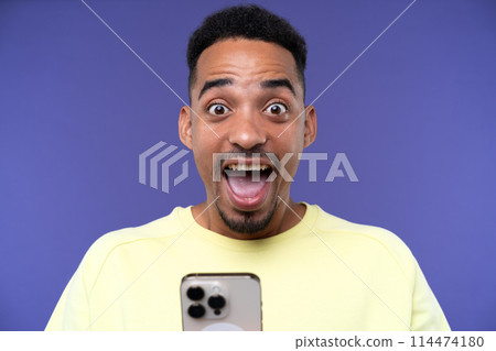 Emotional young black guy in casual raising fists up studio background, celebrating success, happy handsome african american millennial man sharing good emotions, copy space 114474180