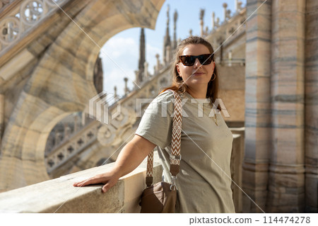 Beautiful 30s woman in sunglasses posing on Roof of Milan Cathedral Duomo di Milano, Italy. Traveling Europe in summer. Attractive blonde female is exploring city. Top tourist attraction. Beautiful 30s woman in sunglasses posing on Roof of Milan Cathedral Duomo di Milano, Italy. Traveling Europe in summer. Attractive blonde female is exploring city. Top tourist attraction. 114474278