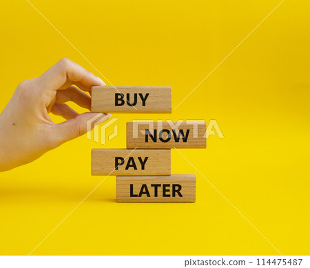 Buy now Pay later symbol. Concept word Buy now Pay later on wooden block. Businessman hand. Beautiful yellow background. Business and Buy now Pay later concept. Copy space Buy now Pay later symbol. Concept word Buy now Pay later on wooden block. Businessman hand. Beautiful yellow background. Business and Buy now Pay later concept. Copy space 114475487