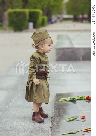 Adorable baby in Soviet military uniform lays a flower on a monument Adorable baby in Soviet military uniform lays a flower on a monument 114475500