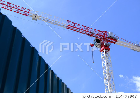 Red and white crane with heart-shaped hook against blue sky. Romantic crane, love-themed equipment, construction site, Valentine's Day concept. Red and white crane with heart-shaped hook against blue sky. Romantic crane, love-themed equipment, construction site, Valentine's Day concept. 114475908