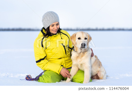 Beautiful girl with lovely young retriever dog outside in winter Beautiful girl with lovely young retriever dog outside in winter 114476004